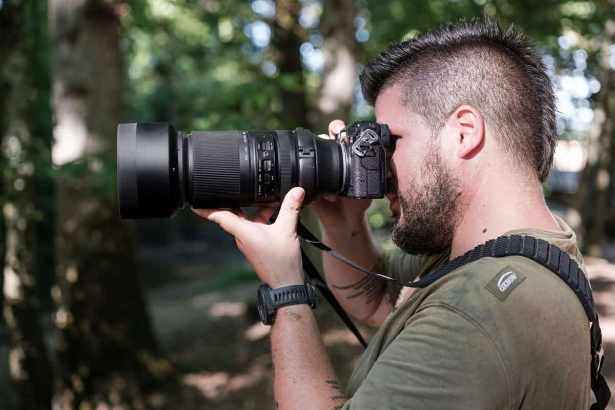 Mann fotografiert mit professioneller Kamera in der Natur.